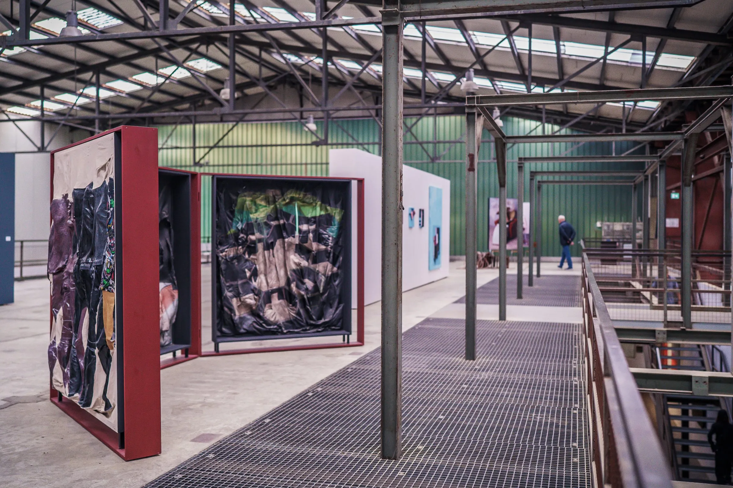 A grating walkway with large red-framed picture panels, the long hall behind