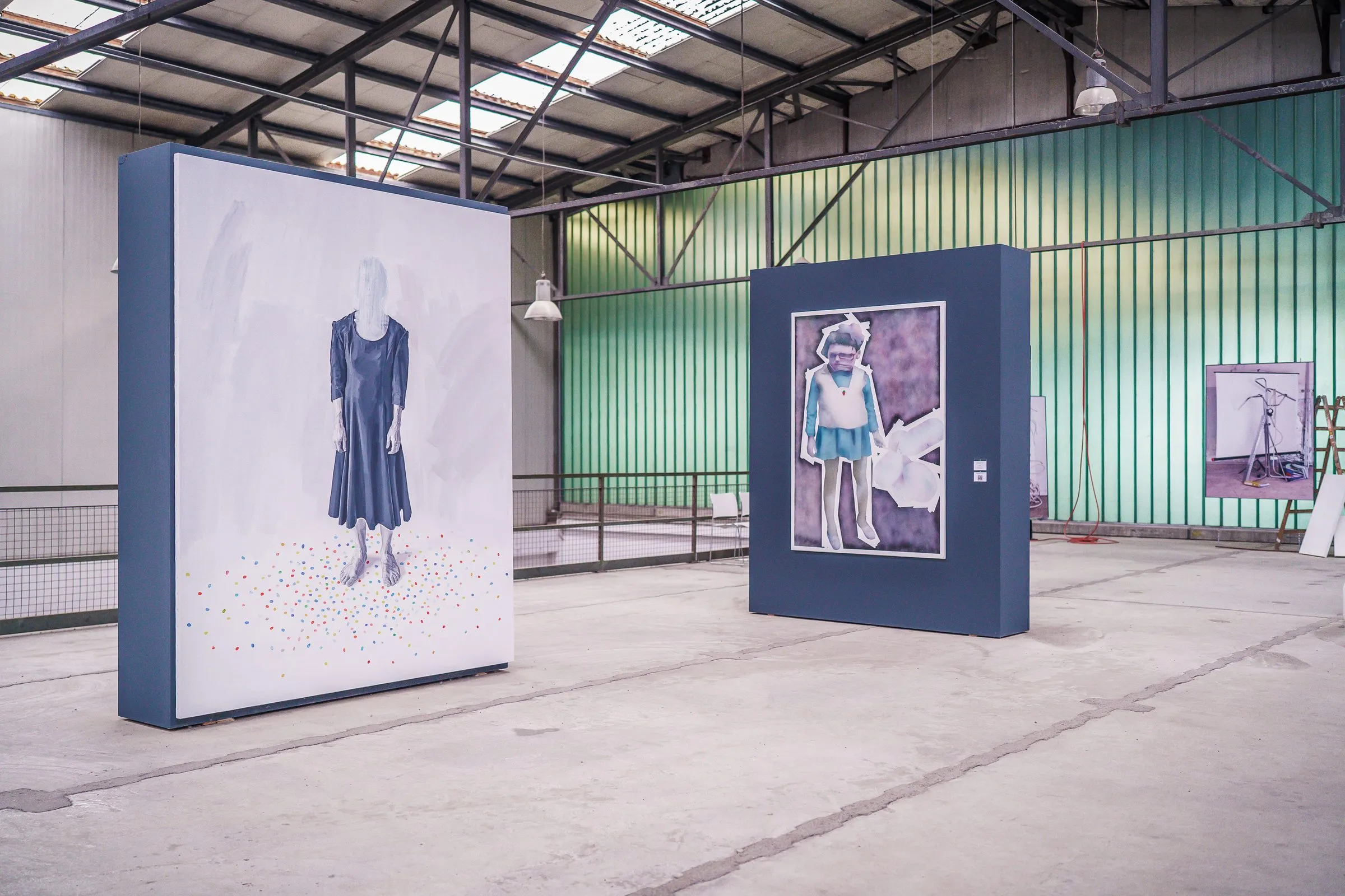 Two free-standing picture panels in a green hall, one showing a woman in a dark dress, the other a girl