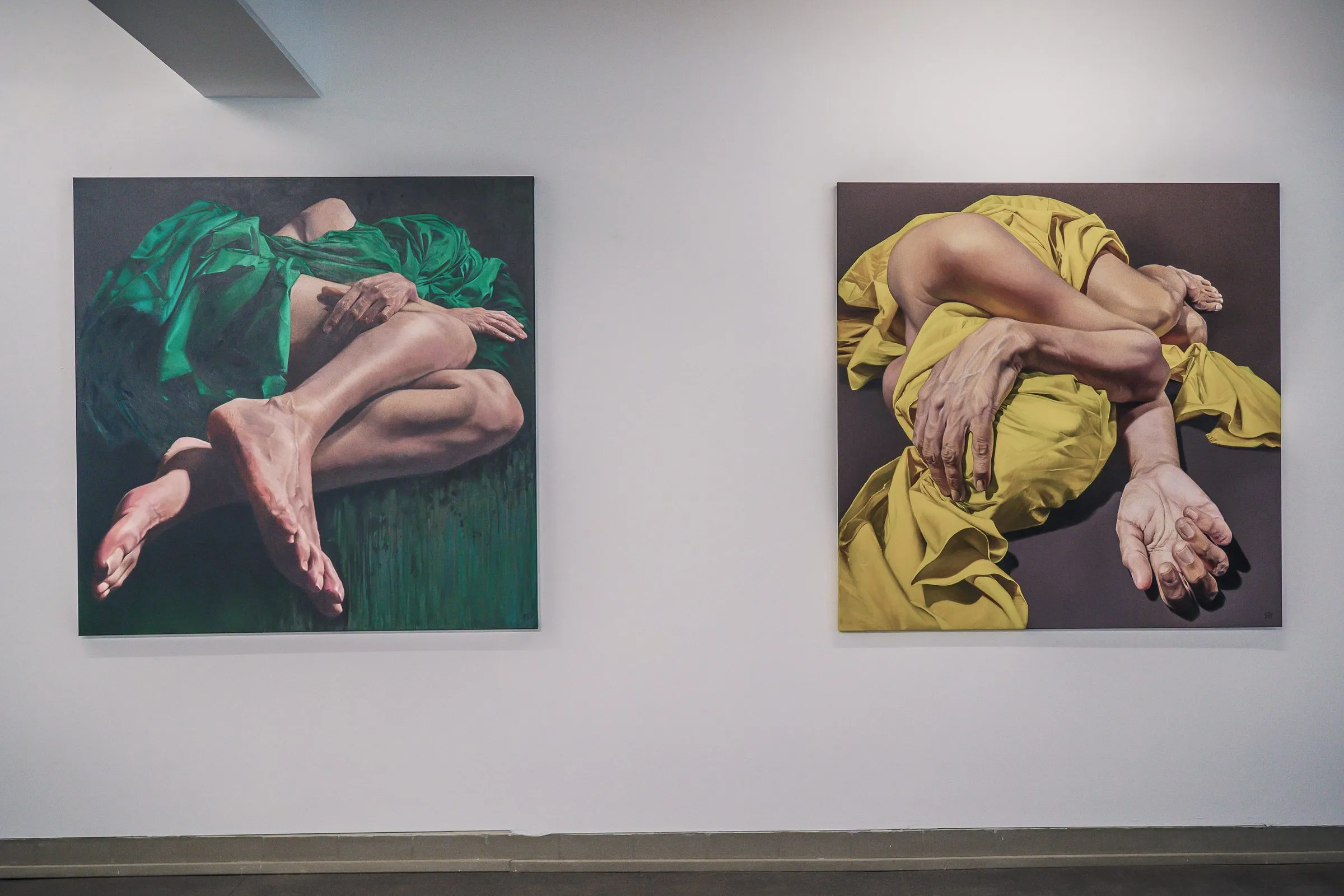 Two paintings: intertwined bodies in green and in yellow fabric, faces hidden