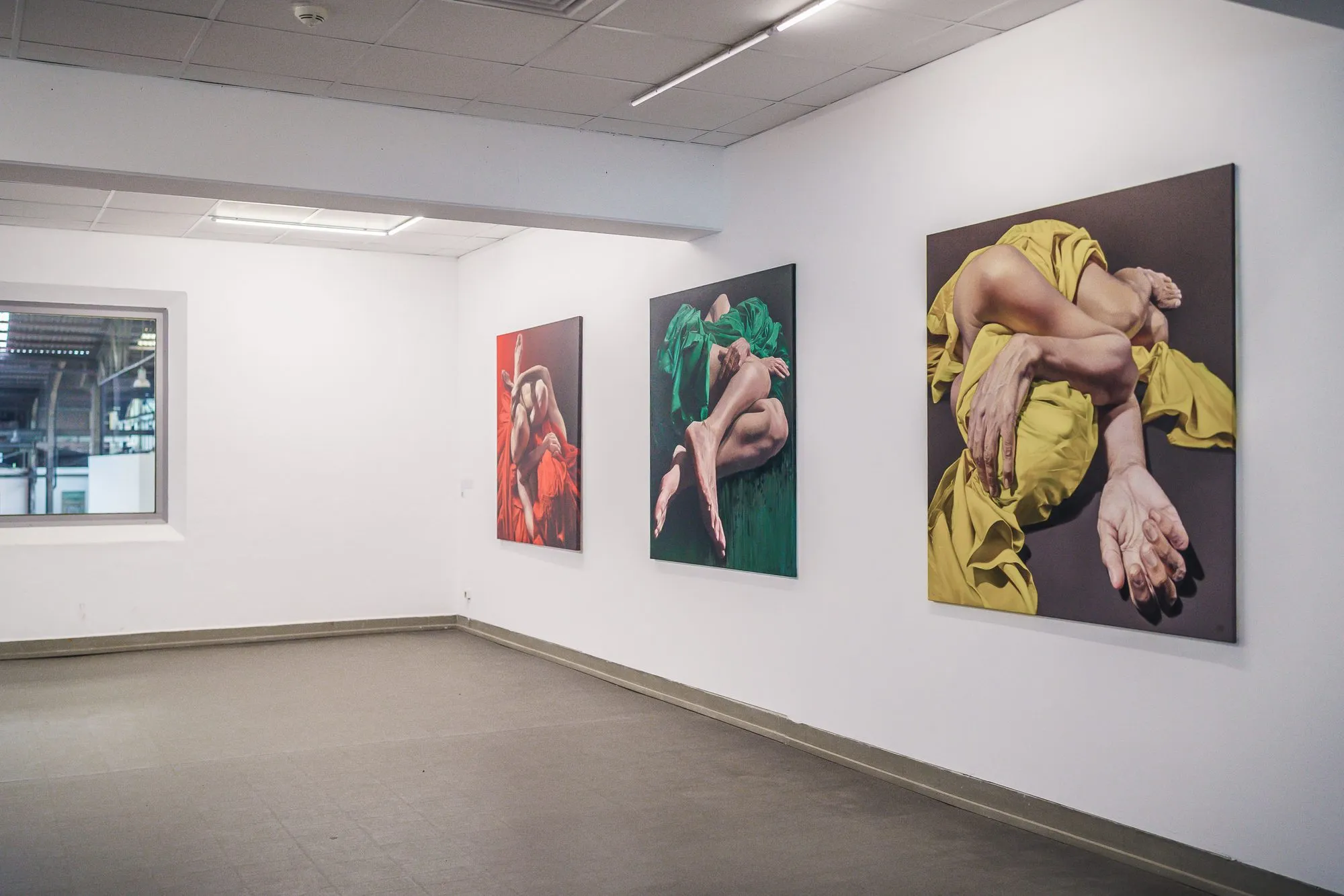 Three paintings by Bego Riba on white walls, bodies in red, green and yellow