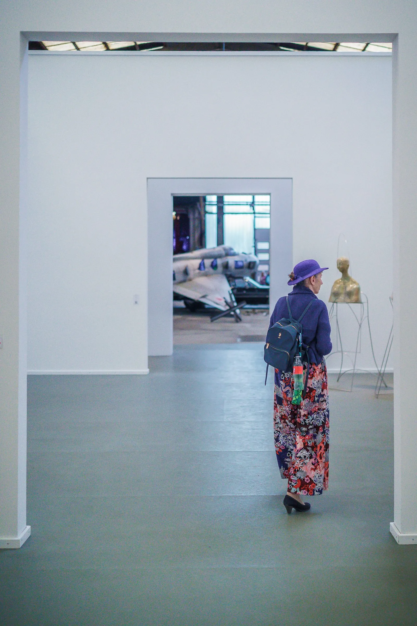 Portrait: a visitor in colourfully patterned trousers walks through a series of white doorways