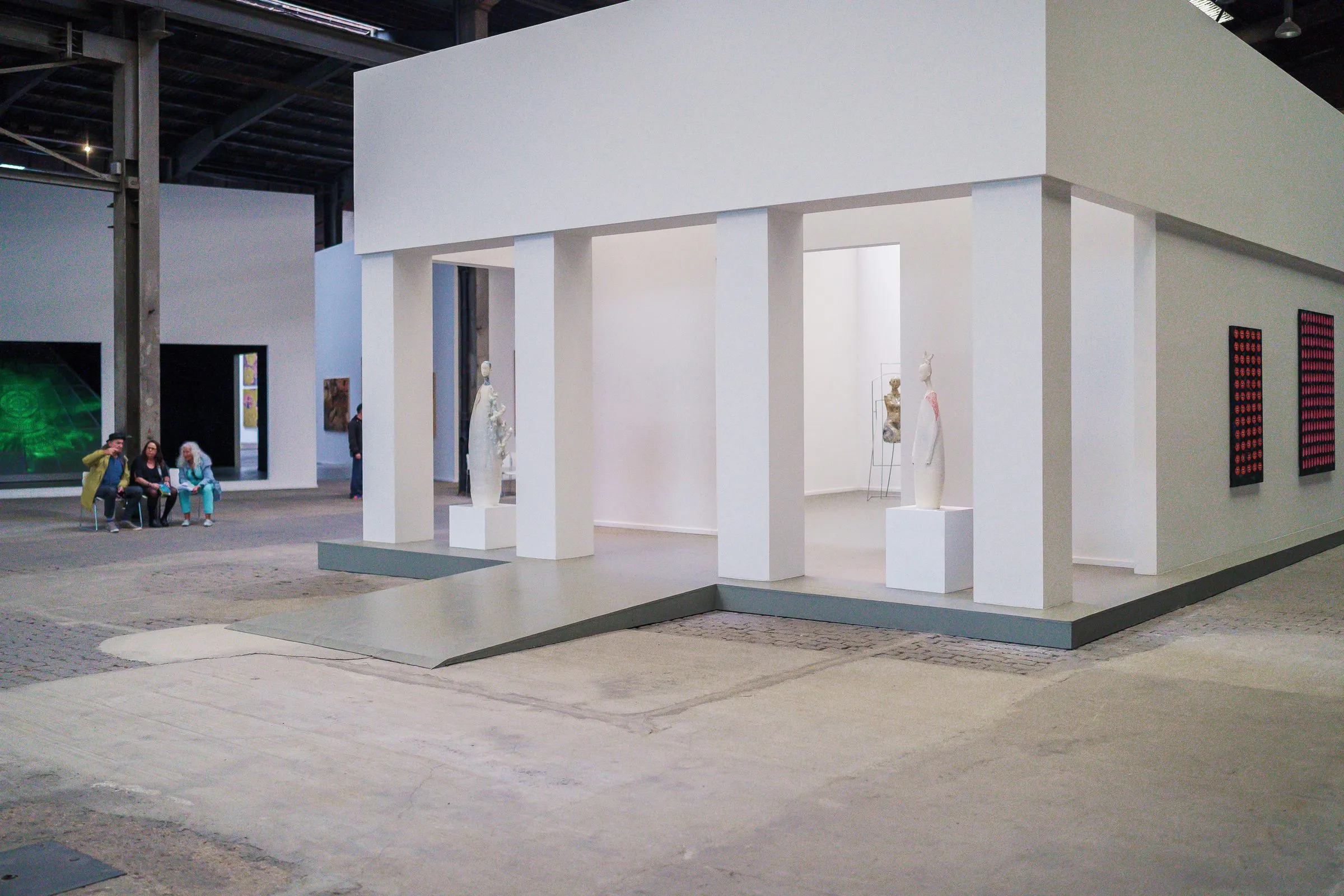 A white pavilion like a small temple with columns in the hall, pale figures inside