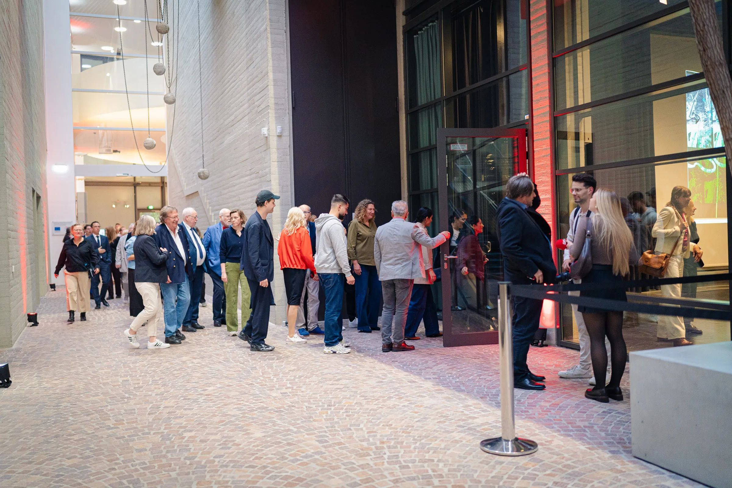 Guests queuing at the entrance of the Sprengel Museum, barrier tape, stone floor, large glass doors