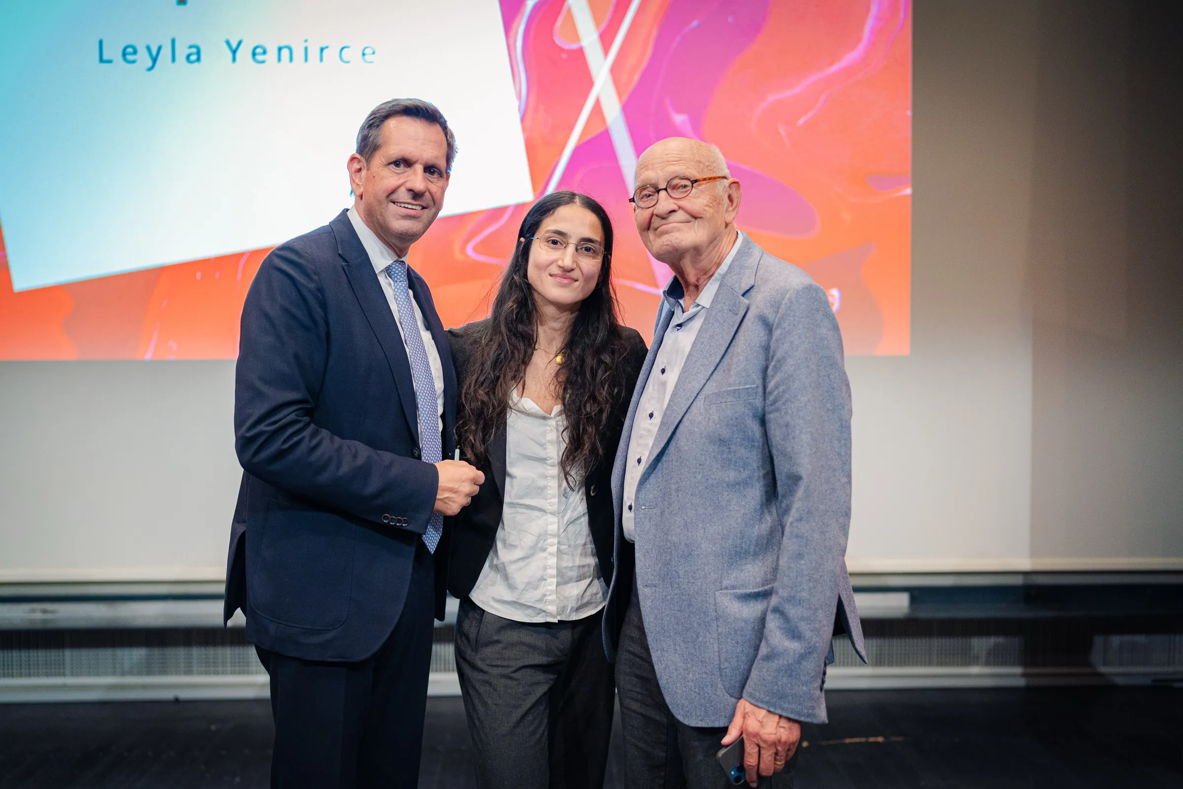 Leyla Yenirce after the award, standing between Minister-President Olaf Lies and Herbert Schmalstieg in front of the red and violet art prize wall