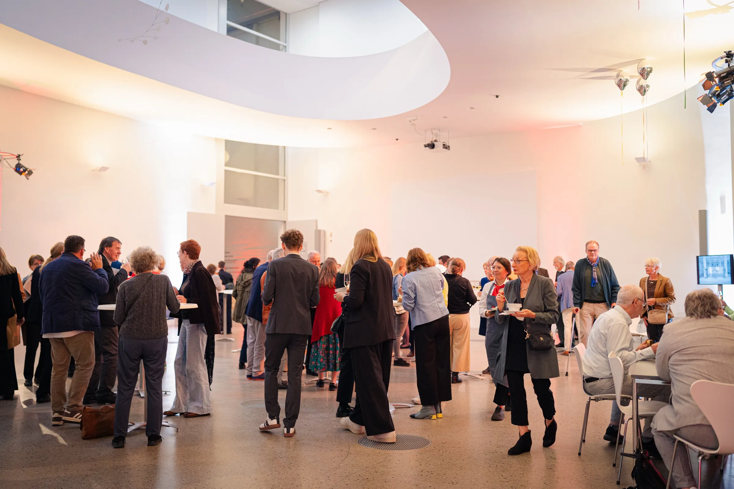 The busy foyer after the award, guests standing in groups under the curved ceiling