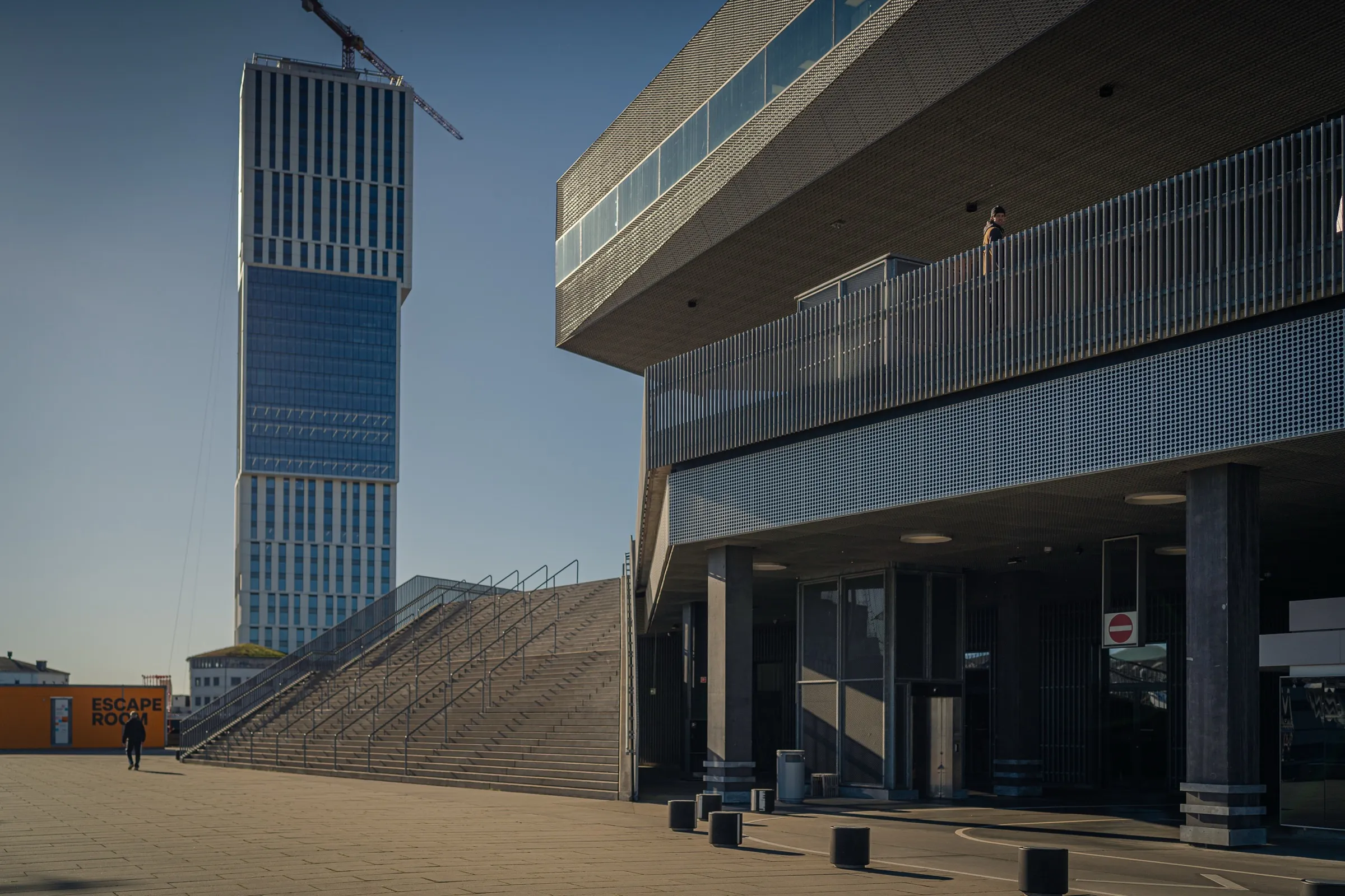 A slender residential tower behind a broad flight of steps and the corner of Dokk1