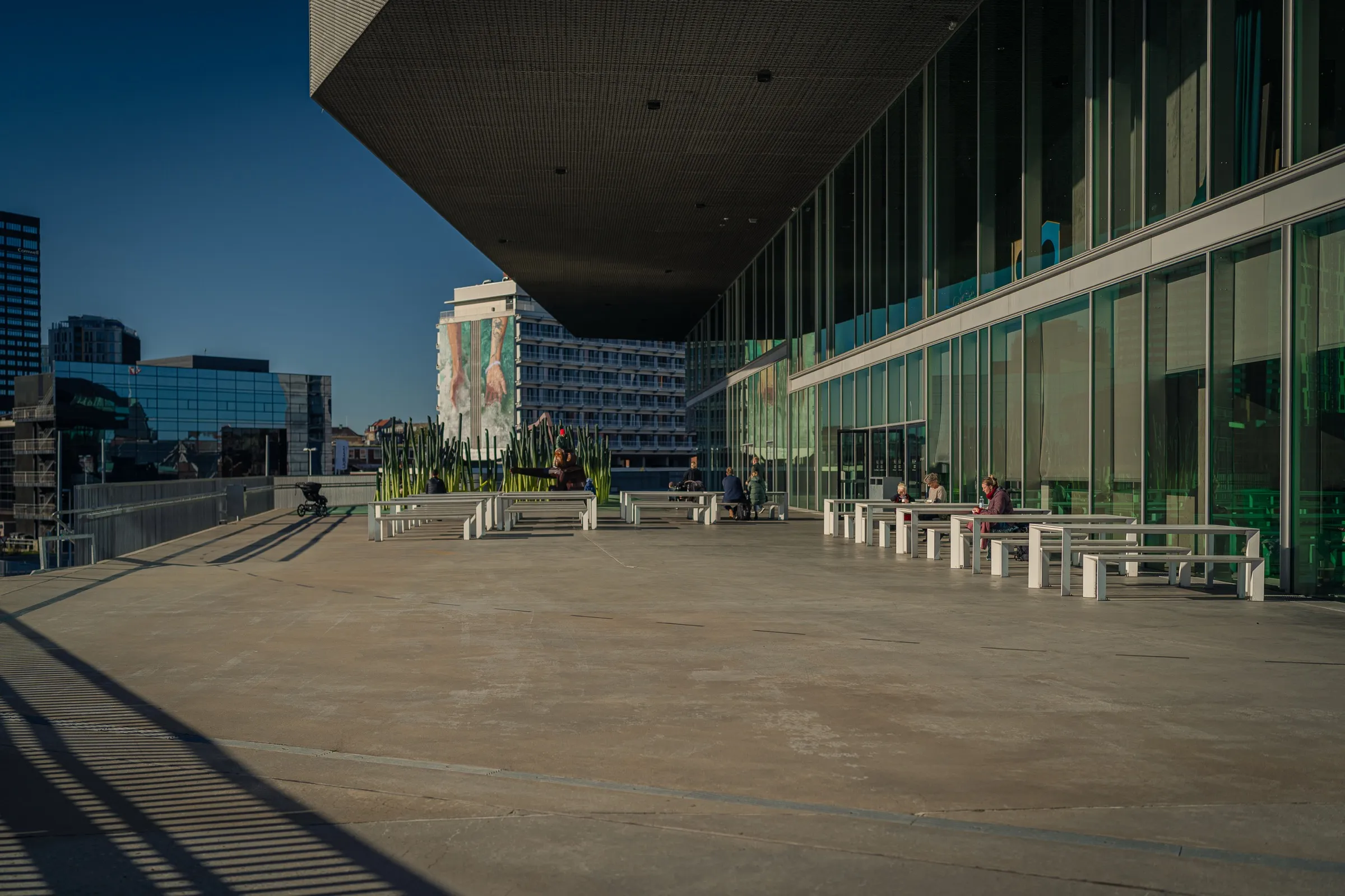 A wide terrace beneath the overhanging roof, glass facade and benches