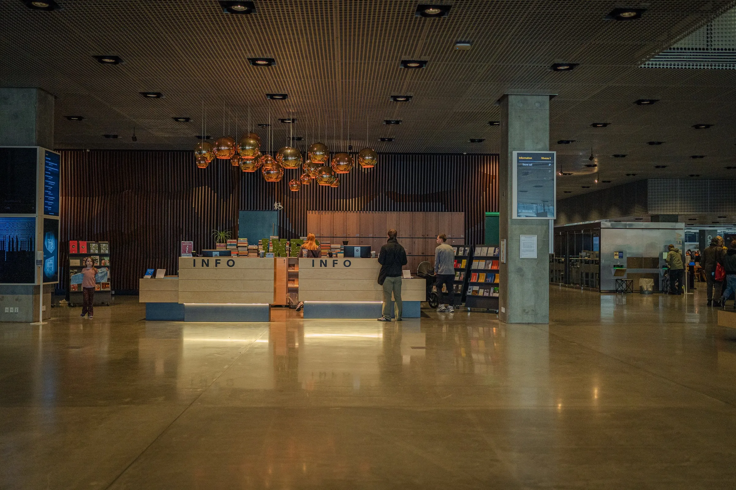A wide foyer with a shiny floor, wooden ceiling and lights above a counter