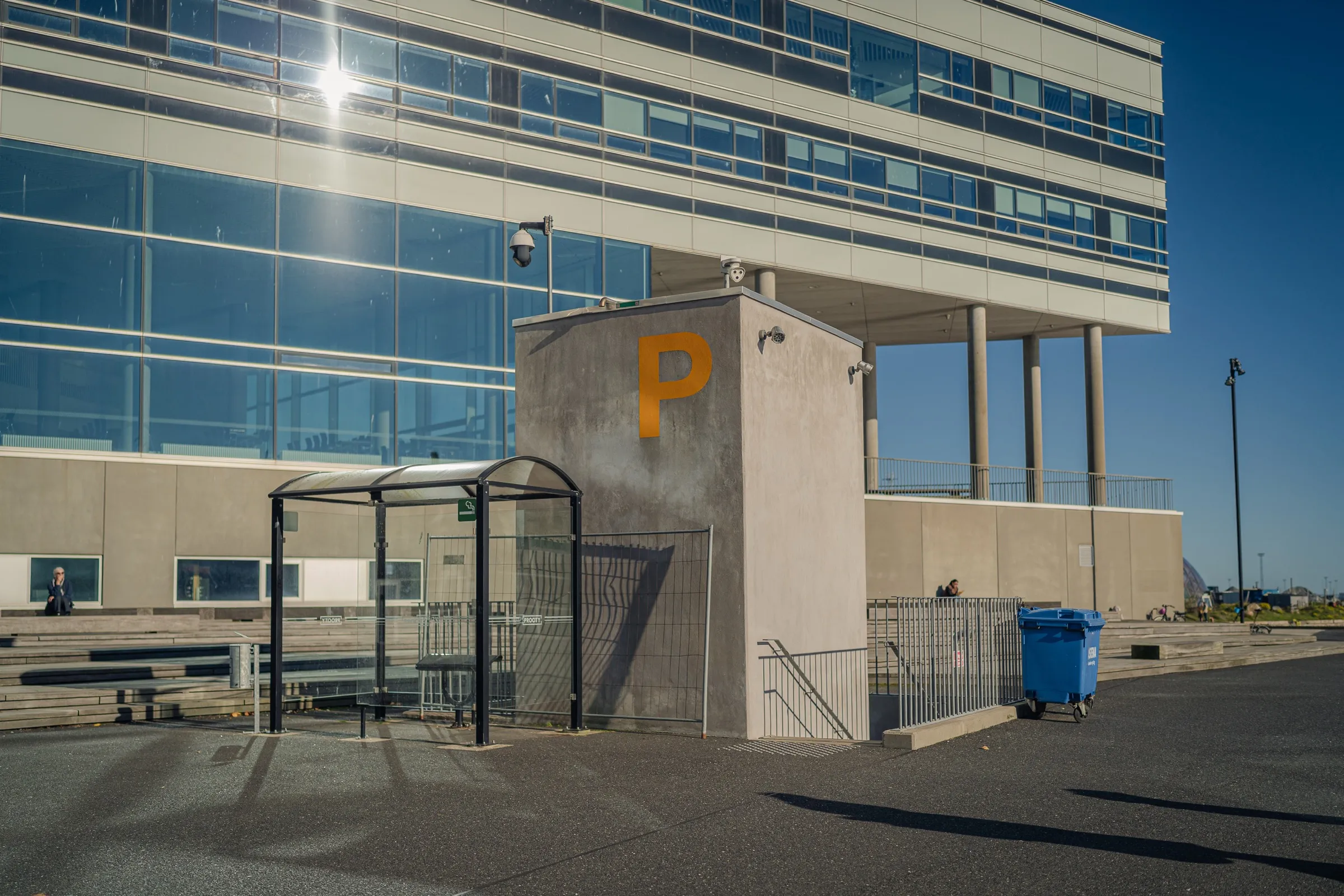 A pale concrete block with a large P, a glass building on slender columns behind
