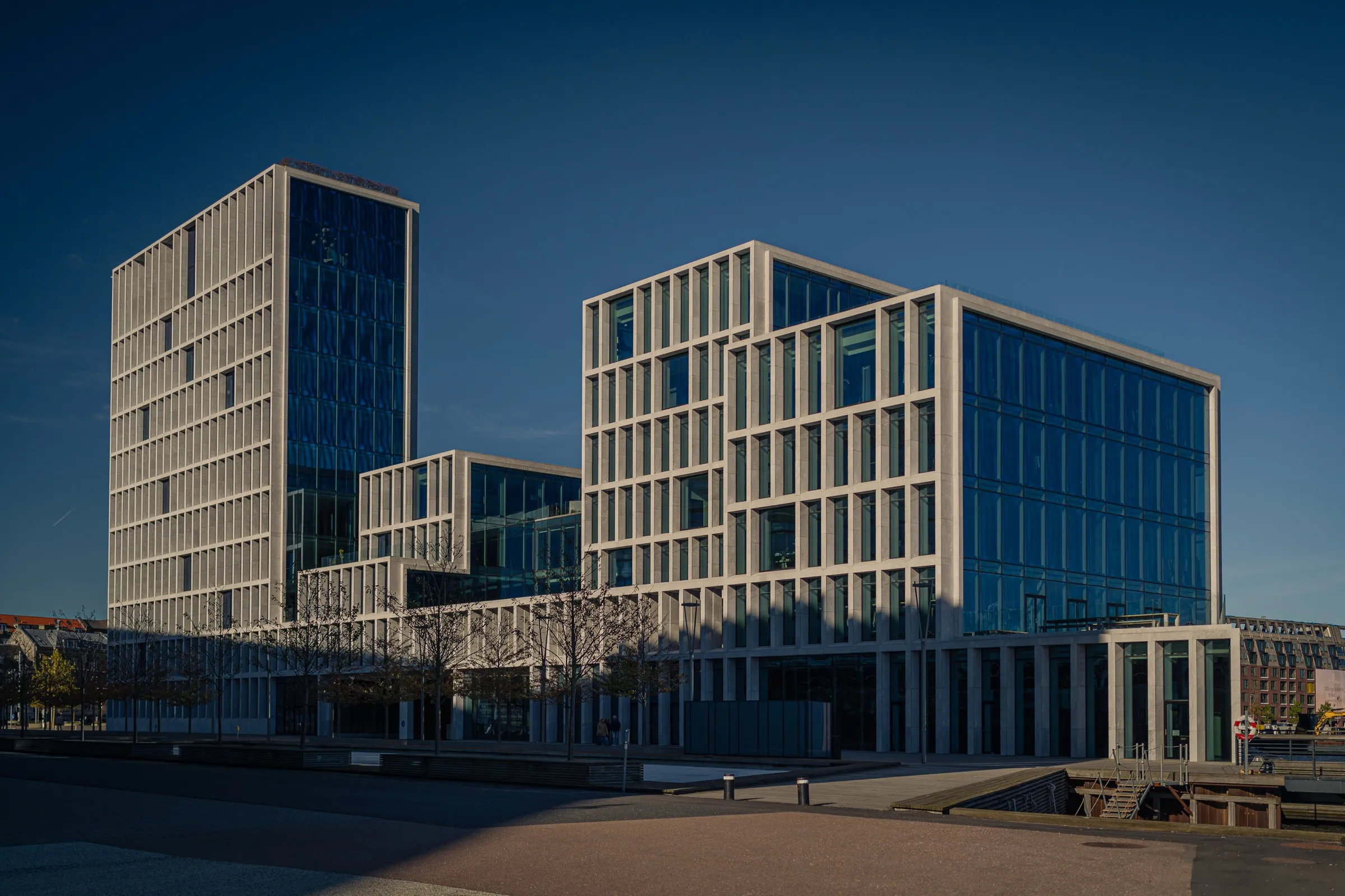 Two office buildings with pale natural stone frames and deep window recesses, a square in front