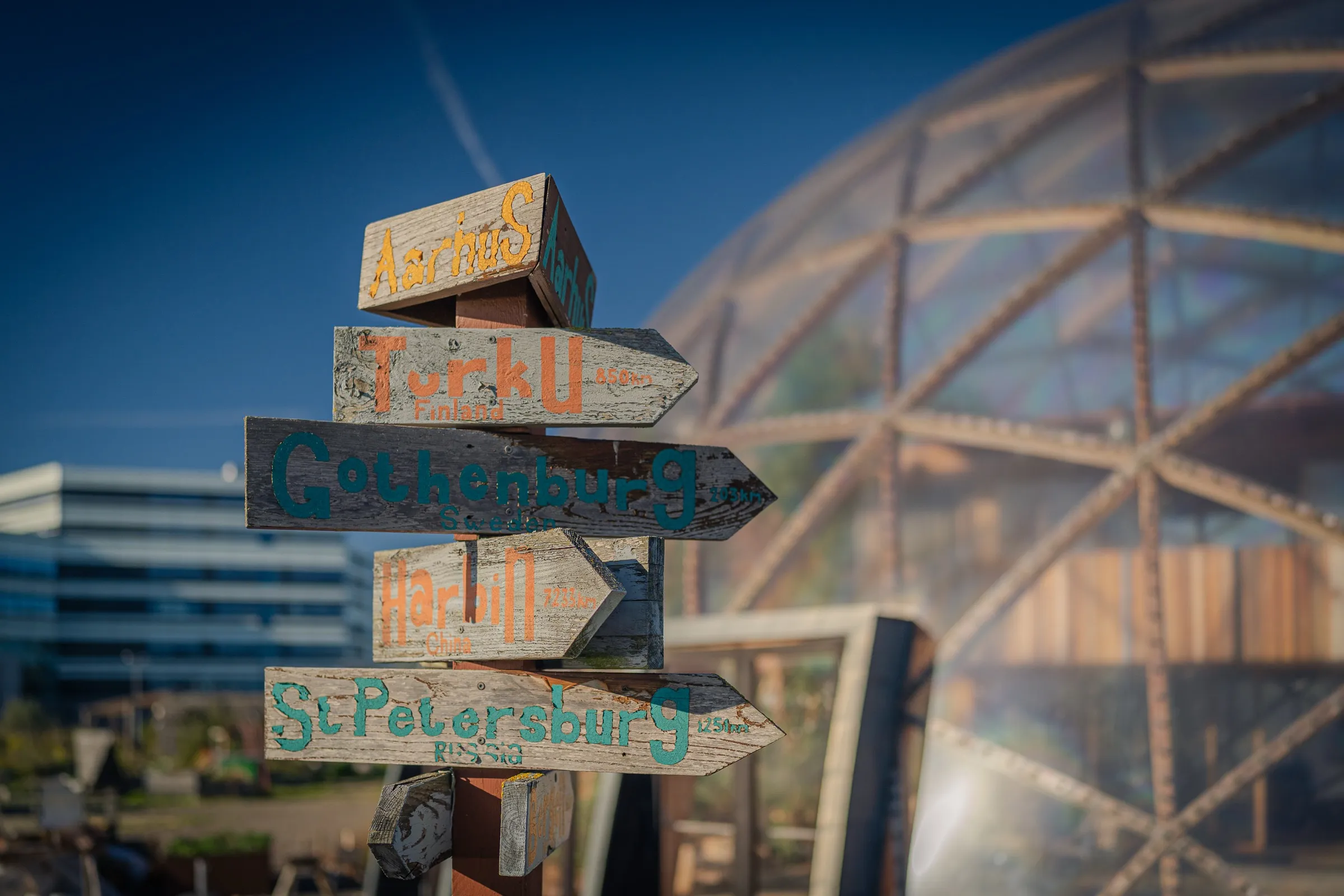 A signpost with hand-painted signs in front of the dome