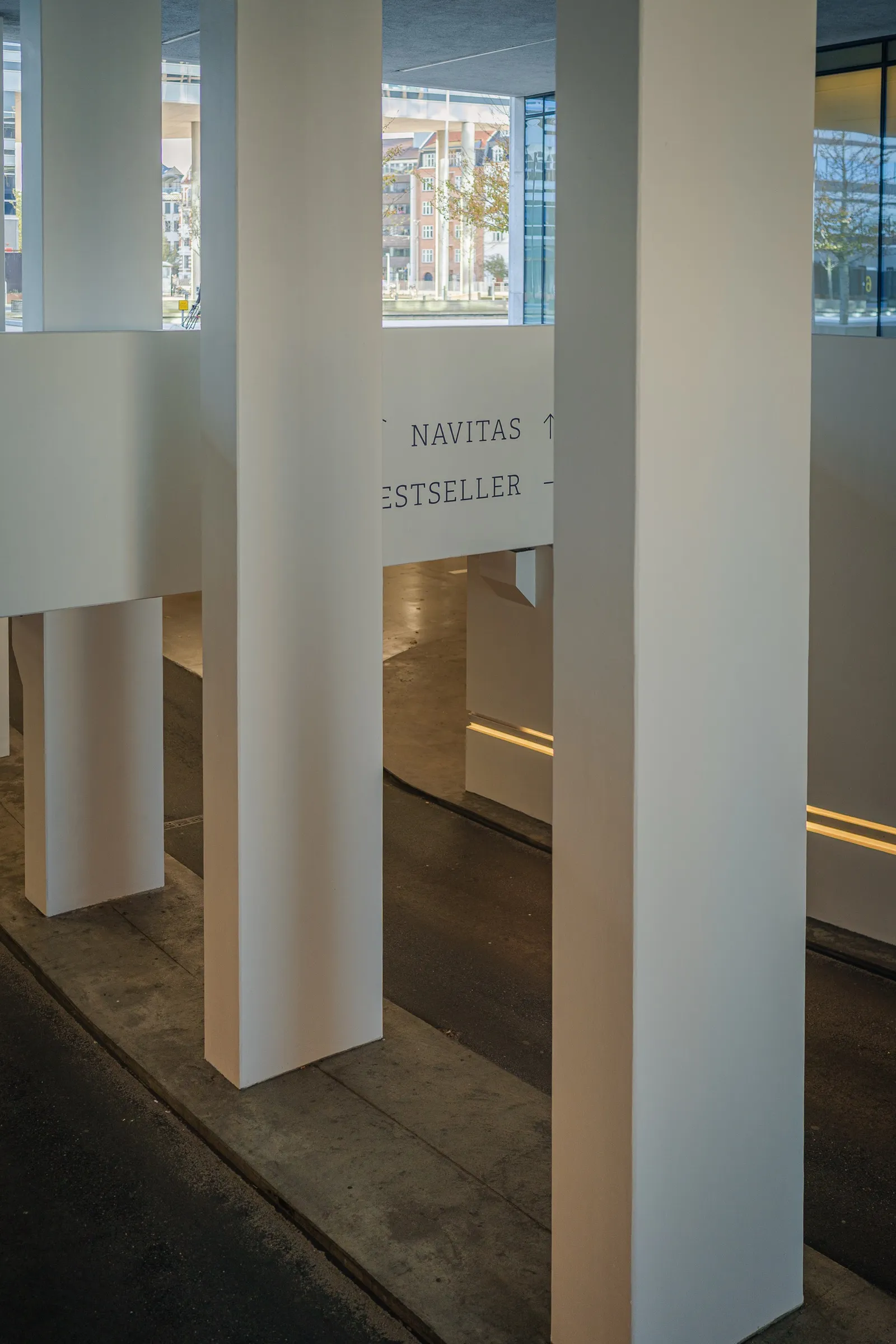 Portrait: white square columns in a bright interior, signs on the wall
