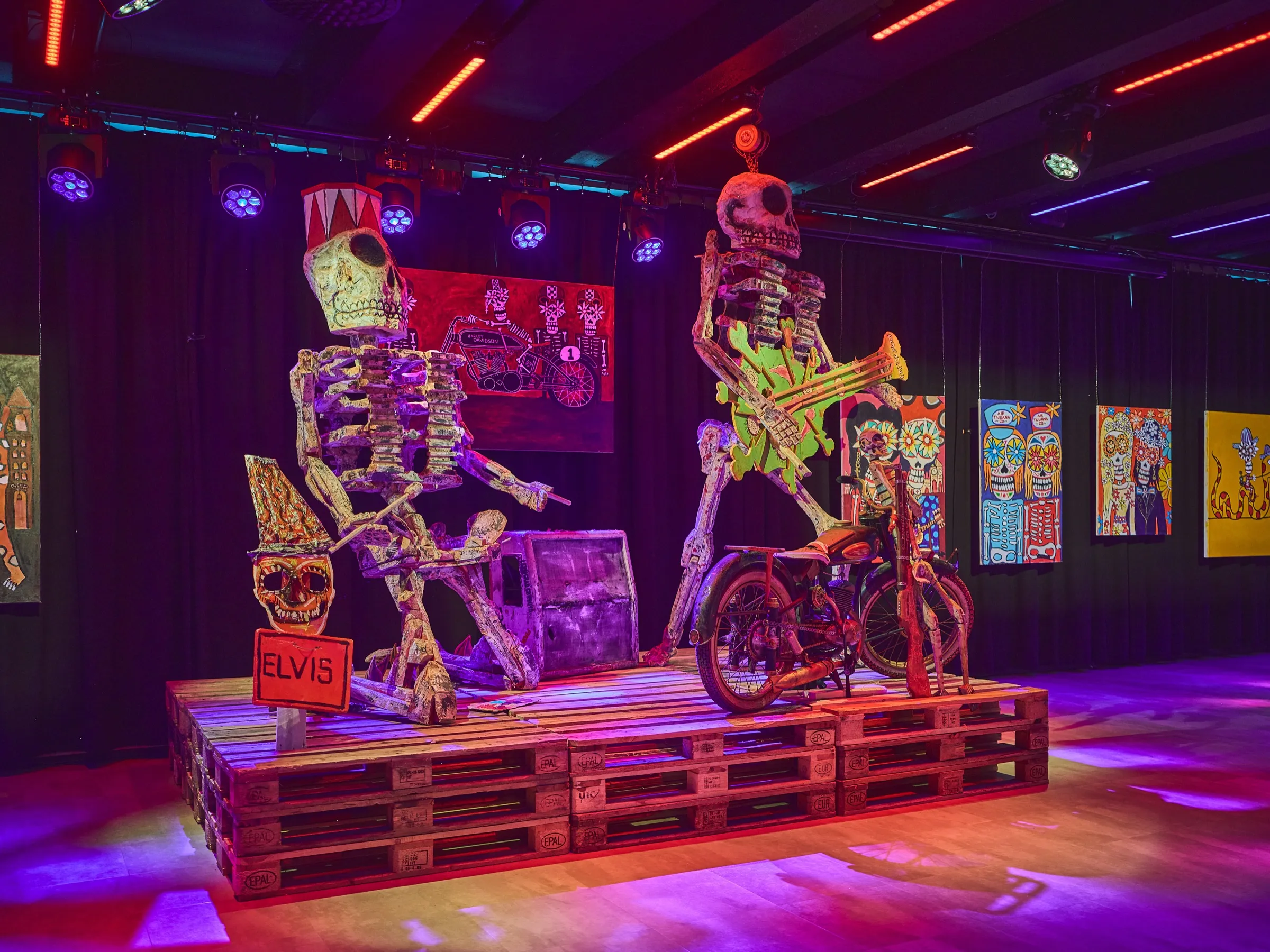 Two large skeleton figures of painted wood, one on a motorcycle