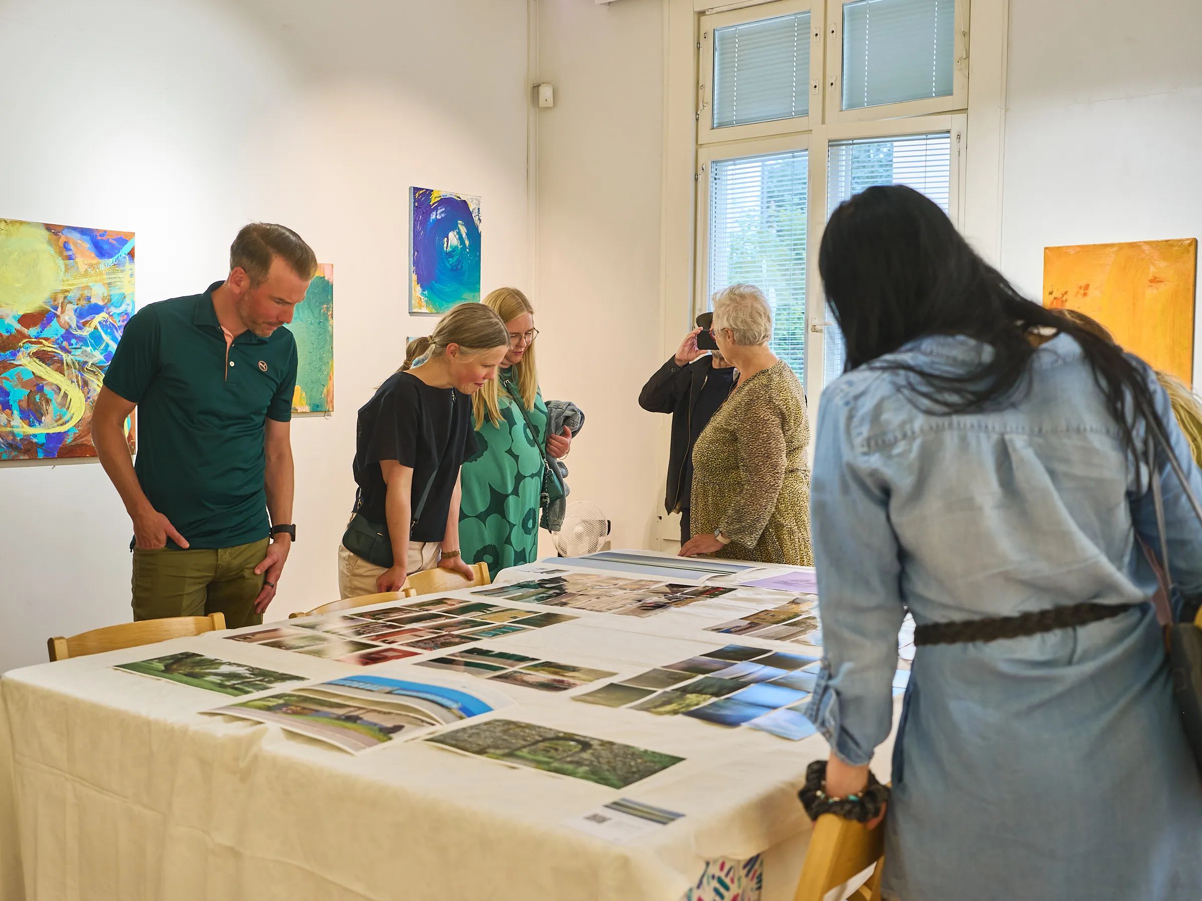 People standing around a long table with photographs laid out