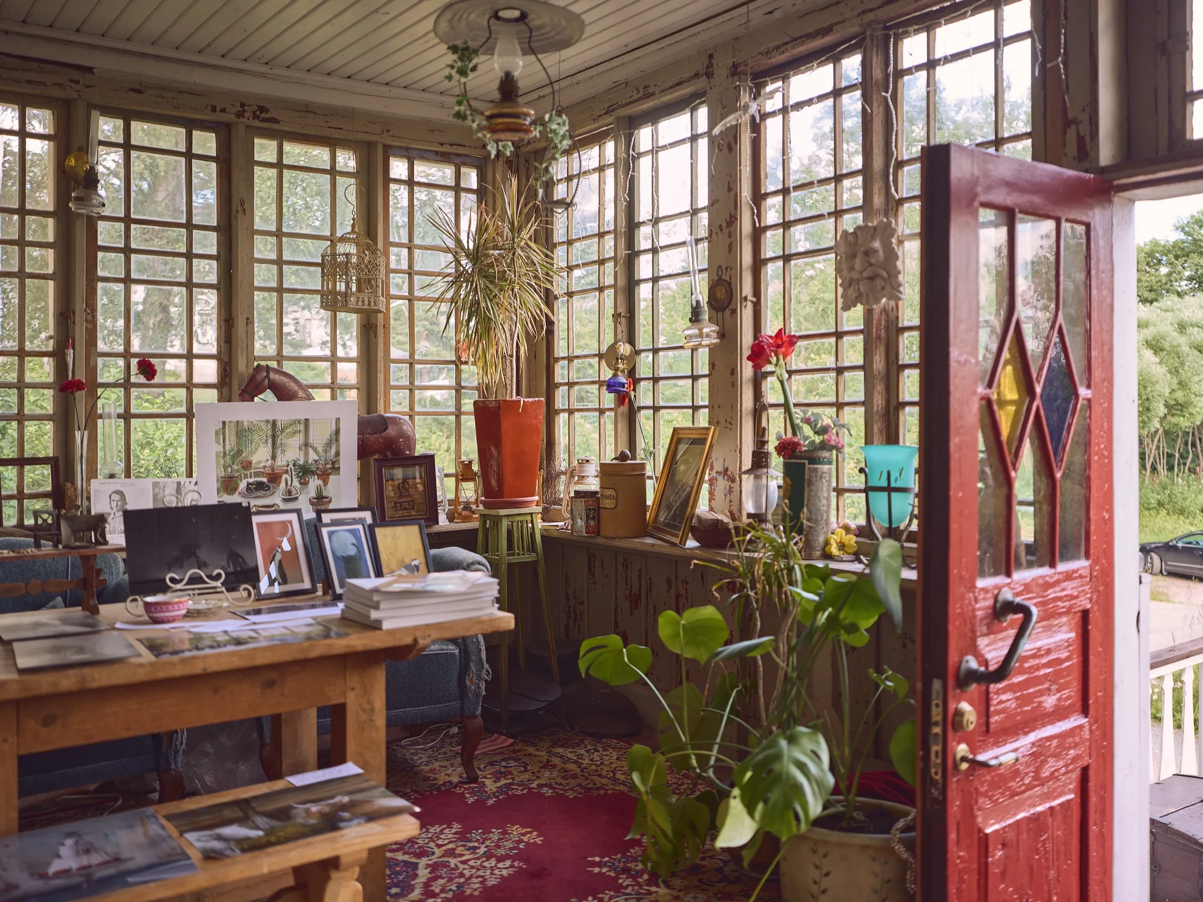 Light-flooded veranda with lattice windows, plants, rugs and a red door