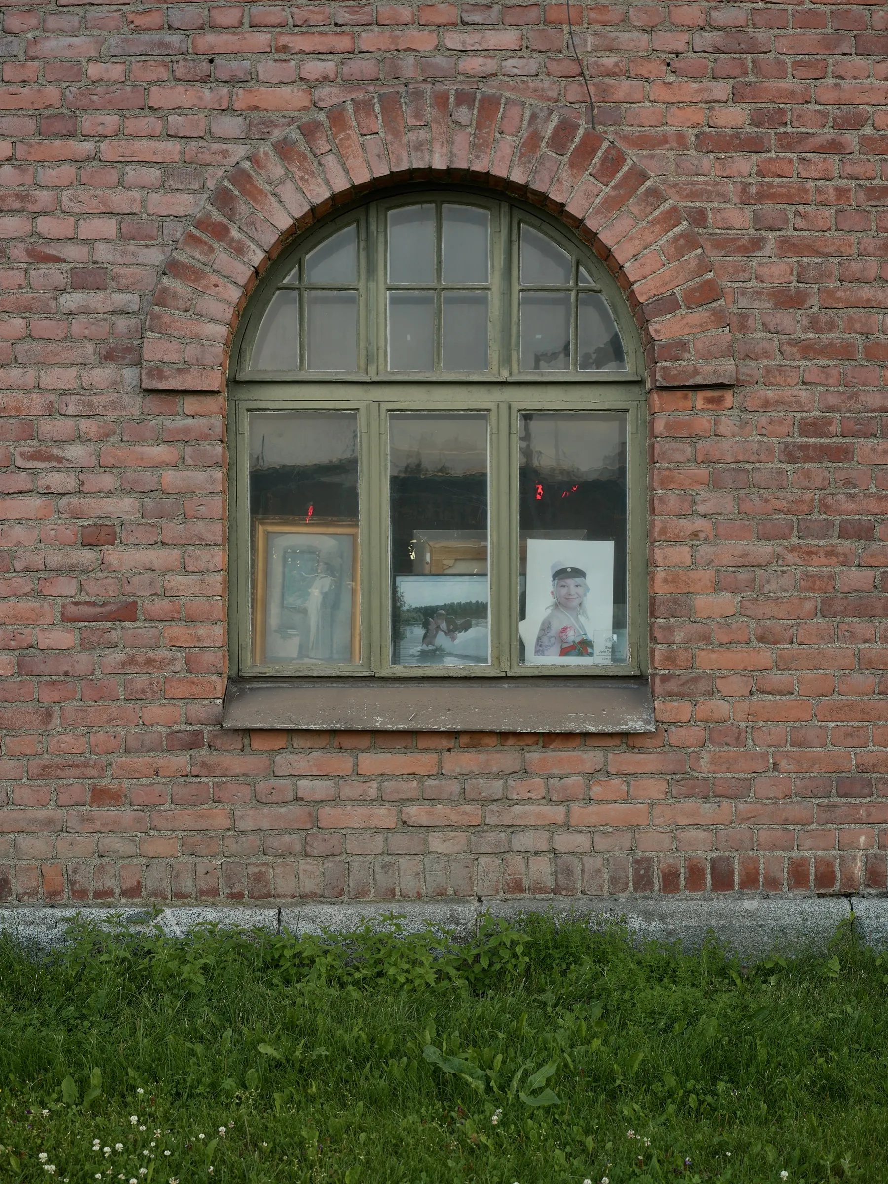 Arched window in the red brickwork, framed pictures leaning inside