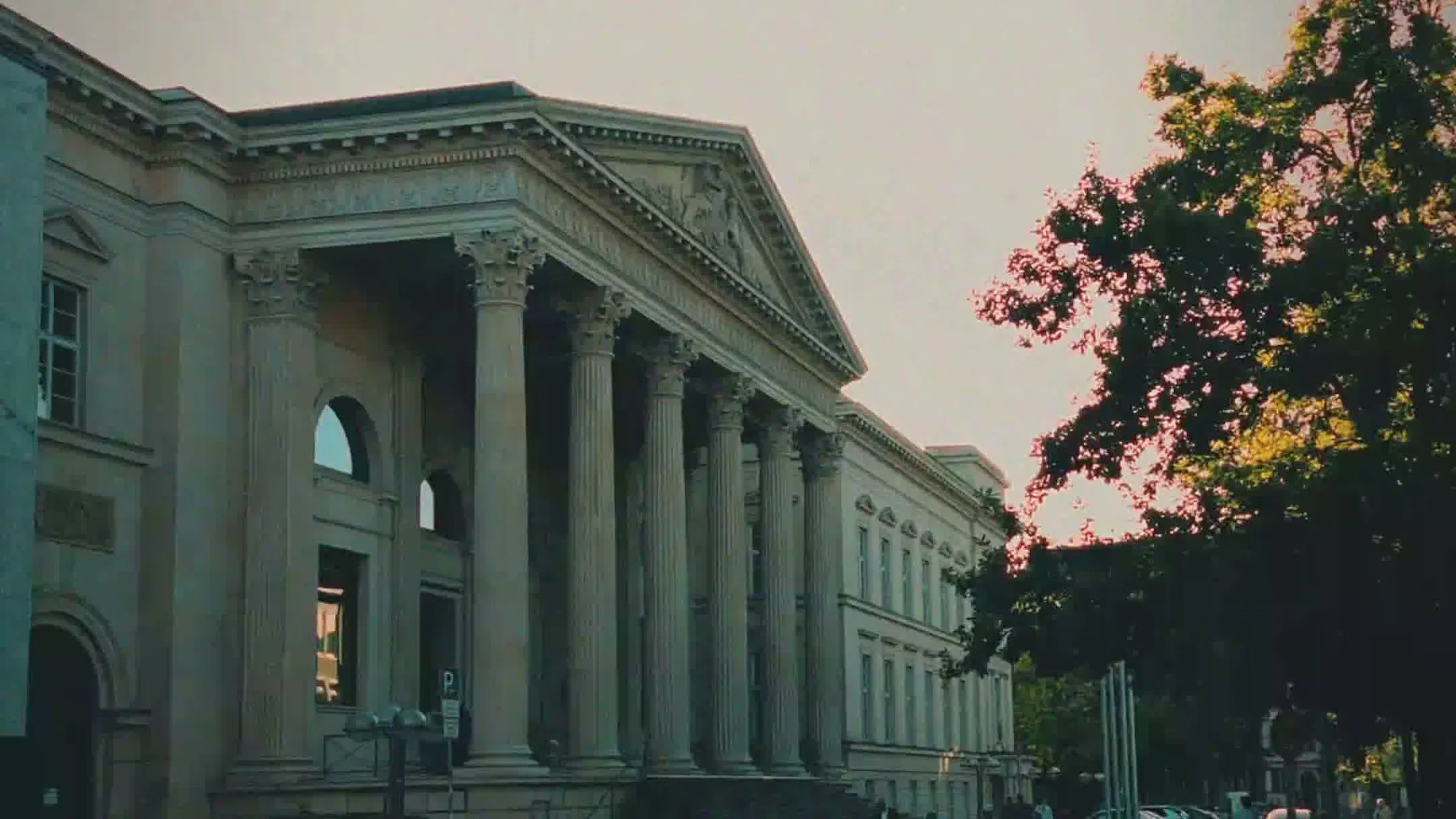 An evening walk through Hanover: a classical facade with columns, a tree in the last light on the right