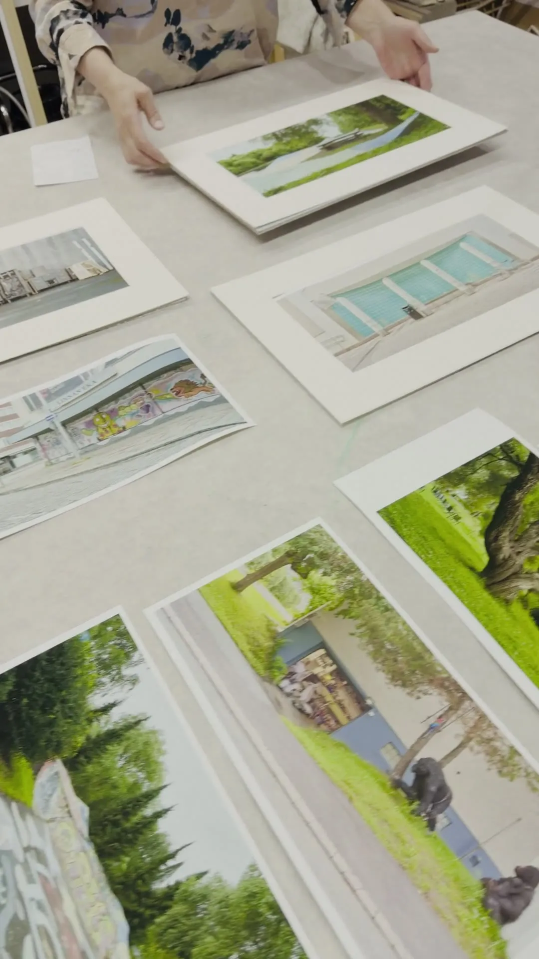 Video: prints in mats lying on the framing workshop's work table, a hand arranging them
